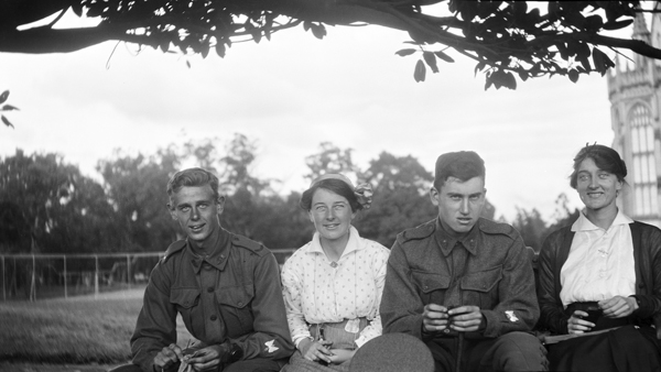 Two  unidentified young men in Australian military uniforms seated with two women.  The woman between the men is Doris Hall [McKellar] and the woman on the right is Pollie Turnbull.  Old Wilson Hall can be seen in background to the right.  Taken in the grounds of the University of Melbourne circa 1917. Photo taken from Doris McKellar’s collection, a student at that time. University of Melbourne Archives, Doris McKellar collection