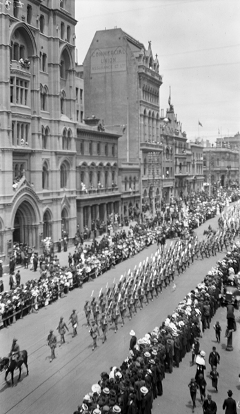 “Military march through Melbourne A.I.F.”.  Australian Imperial Forces parade along Collins Street, Melbourne, watched by onlookers behind barricades.  The Commercial Union Assurance Co Ltd building is prominent. Photo taken by Doris McKellar, a student at that time. University of Melbourne Archives, Doris McKellar collection